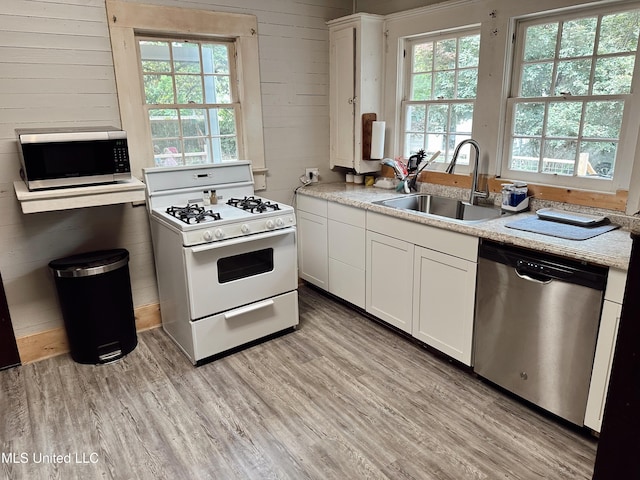 90 Holmes St, Lucedale, MS 39452 - kitchen featuring stainless steel appliances, a sink, plenty of natural light, light wood finished floors, and wooden walls
