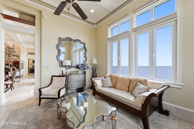 living area featuring stone tile floors, baseboards, ceiling fan, ornamental molding, and recessed lighting