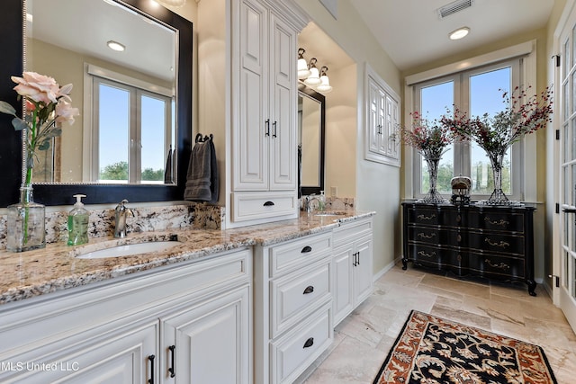 full bath featuring double vanity, a sink, and stone tile flooring