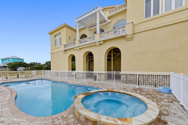 view of swimming pool featuring a pool with connected hot tub, fence, and a patio