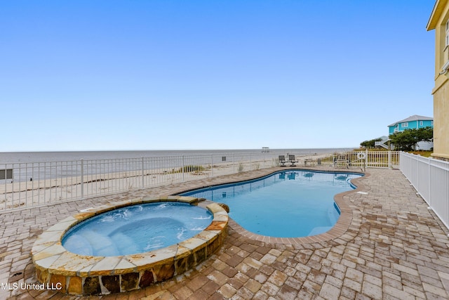 view of pool featuring a patio area, a fenced backyard, a pool with connected hot tub, and a water view