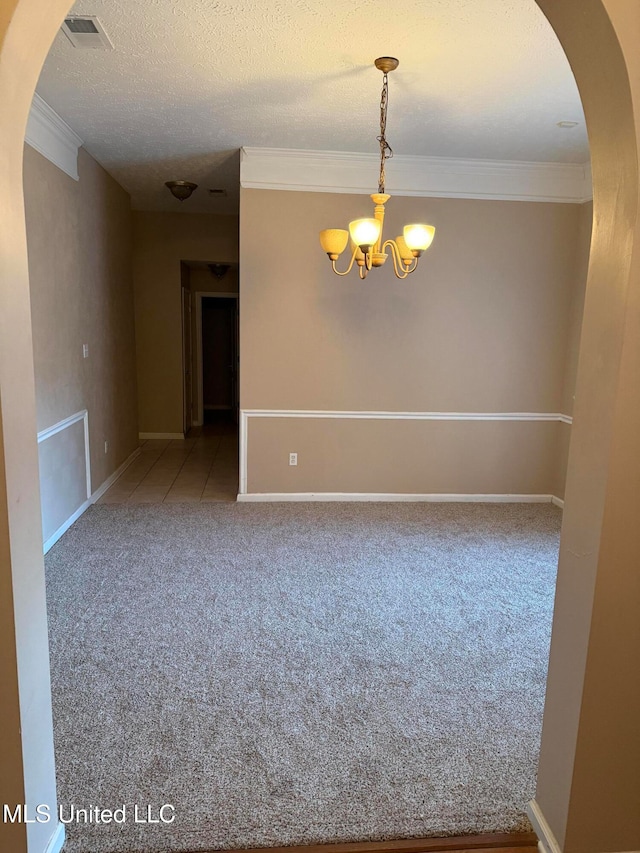 carpeted empty room featuring crown molding, a notable chandelier, and a textured ceiling