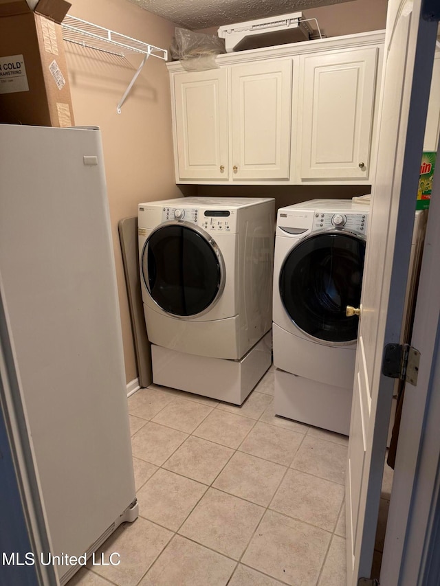 clothes washing area featuring cabinets, light tile patterned floors, and independent washer and dryer