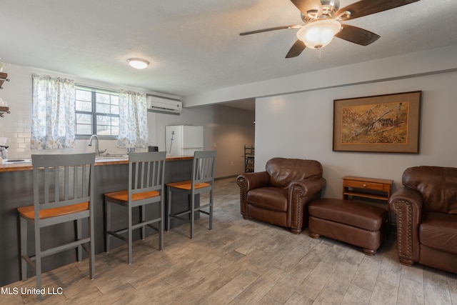 95 Nesting Site, Vicksburg, MS 39183 - living room featuring an AC wall unit, a ceiling fan, light wood-type flooring, and a textured ceiling