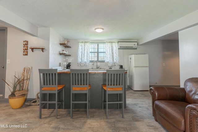 95 Nesting Site, Vicksburg, MS 39183 - kitchen featuring a wall unit AC, a peninsula, freestanding refrigerator, a sink, and a kitchen breakfast bar