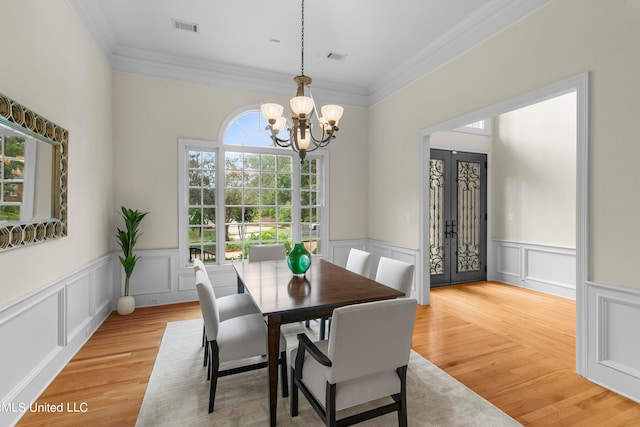 dining area featuring ornamental molding, a chandelier, light wood-type flooring, and french doors