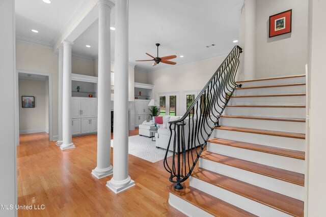 stairway with ornamental molding, wood-type flooring, ornate columns, and ceiling fan