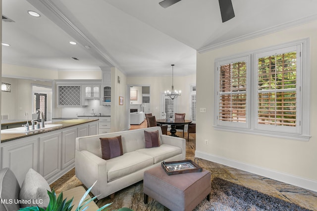 living room featuring crown molding, sink, lofted ceiling, and ceiling fan with notable chandelier