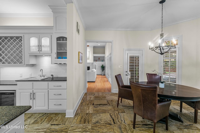 dining room featuring crown molding, a notable chandelier, sink, and beverage cooler