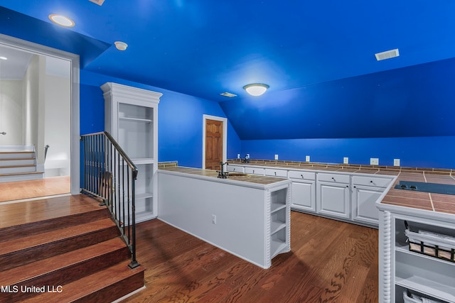 kitchen featuring tile counters, sink, vaulted ceiling, white cabinets, and dark hardwood / wood-style flooring