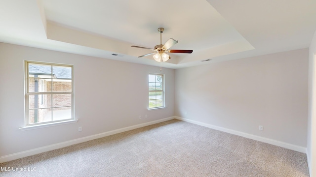 carpeted spare room featuring a tray ceiling and ceiling fan