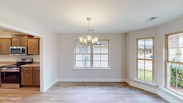 kitchen featuring stainless steel appliances, light hardwood / wood-style flooring, decorative light fixtures, and an inviting chandelier