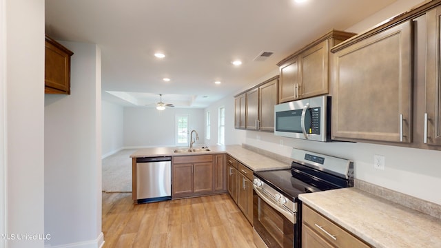 kitchen featuring kitchen peninsula, sink, light wood-type flooring, appliances with stainless steel finishes, and ceiling fan