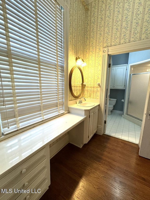 bathroom featuring hardwood / wood-style floors, vanity, toilet, and a shower with shower door