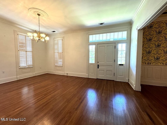 foyer with ornamental molding, dark wood-type flooring, and an inviting chandelier