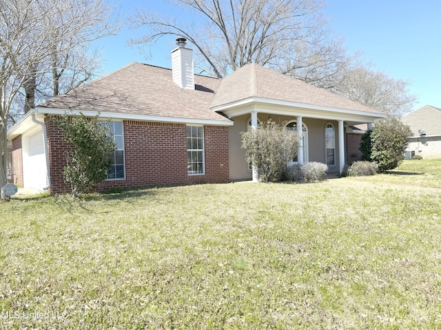 rear view of house featuring a garage, a yard, brick siding, and a chimney