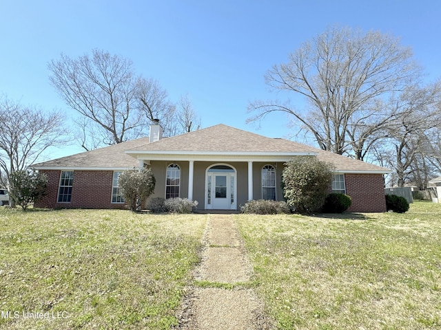 view of front of home featuring a front lawn, stucco siding, brick siding, and a chimney