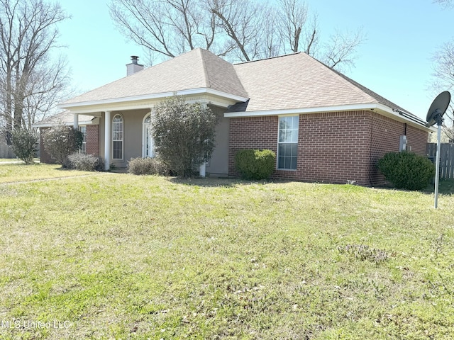 exterior space with a front lawn, brick siding, roof with shingles, and a chimney