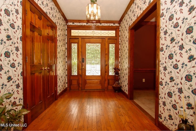 entryway featuring a notable chandelier, ornamental molding, and hardwood / wood-style flooring