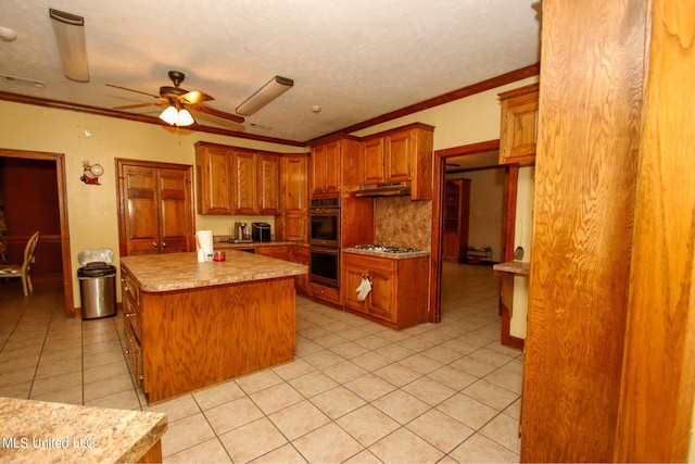 kitchen featuring ornamental molding, a center island, light tile patterned floors, appliances with stainless steel finishes, and ceiling fan