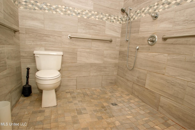 bathroom featuring tile walls, a tile shower, and toilet