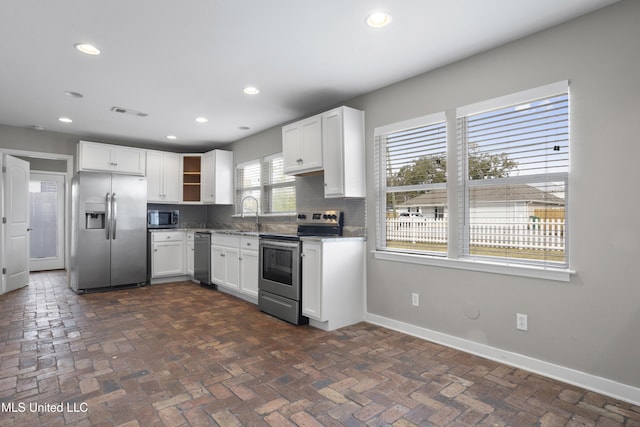 kitchen featuring stainless steel appliances, white cabinetry, sink, and backsplash