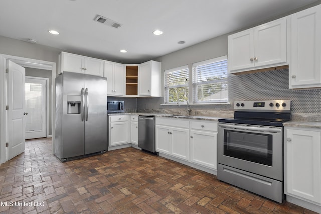 kitchen with stainless steel appliances, white cabinets, decorative backsplash, and sink