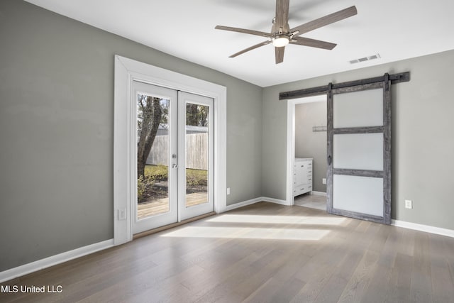 empty room featuring hardwood / wood-style flooring, ceiling fan, and a barn door