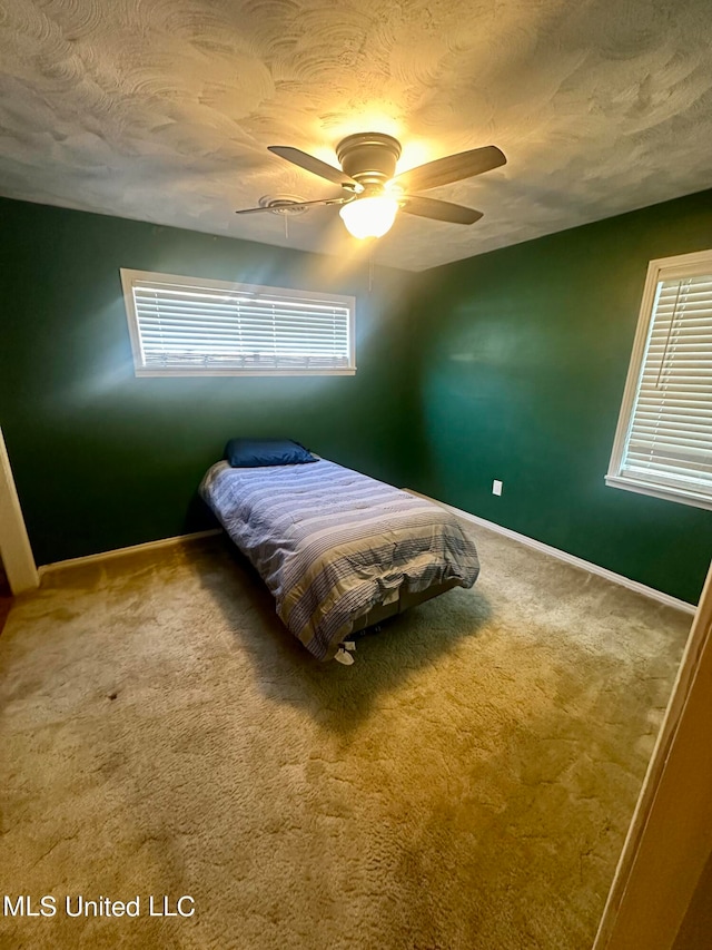 carpeted bedroom with ceiling fan and a textured ceiling