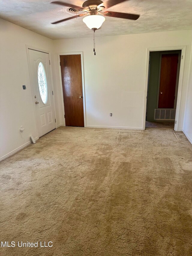 carpeted foyer featuring a textured ceiling and ceiling fan