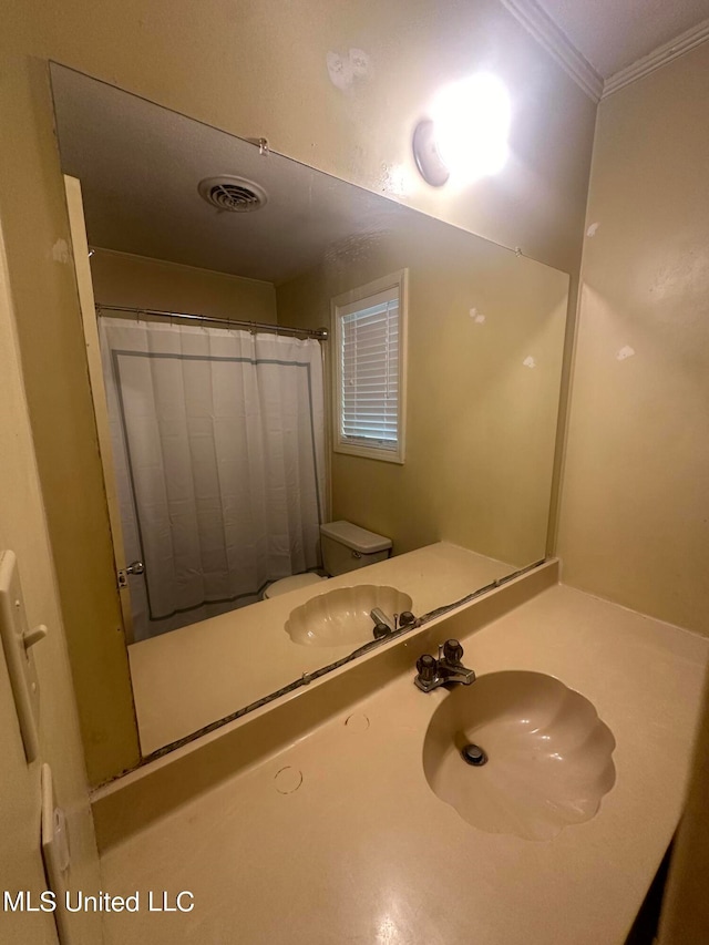 bathroom featuring toilet, ornamental molding, a shower with curtain, and sink