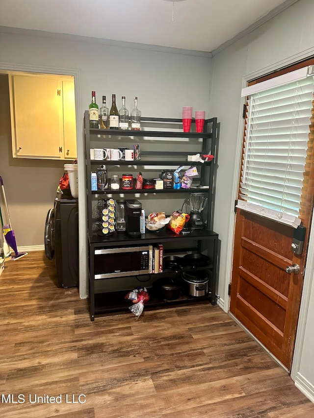 bar with washer / dryer, ornamental molding, and dark hardwood / wood-style flooring