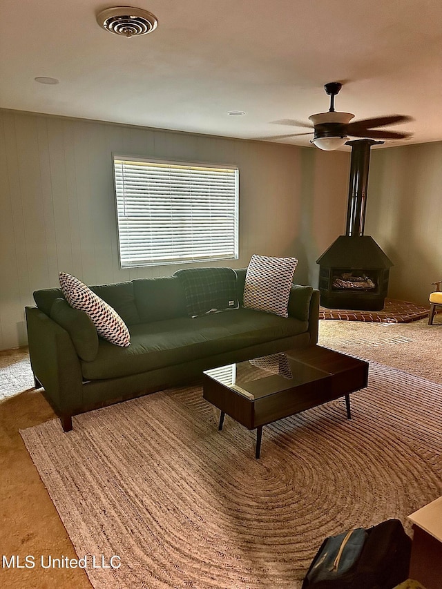 living room with a wood stove and ceiling fan