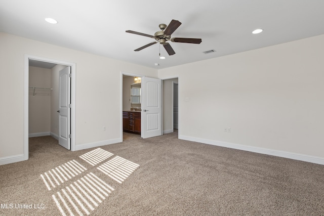 unfurnished bedroom with a walk in closet, ensuite bath, a closet, and light carpet