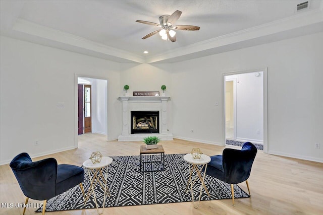 602 Hathaway Dr, Clinton, MS 39056 - living room featuring a raised ceiling, light wood-style flooring, ceiling fan, ornamental molding, and a fireplace with raised hearth