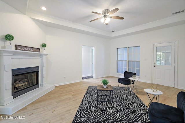 602 Hathaway Dr, Clinton, MS 39056 - living room with crown molding, light wood-style flooring, ceiling fan, a glass covered fireplace, and a tray ceiling