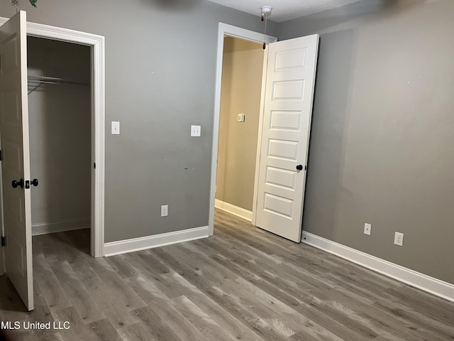 unfurnished bedroom featuring a closet, wood finished floors, and baseboards