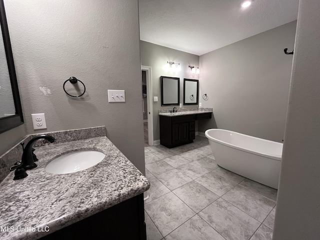 bathroom with a freestanding bath, two vanities, and a sink