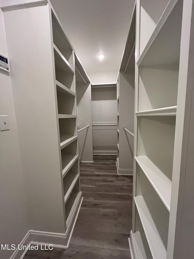 walk in closet with dark wood-style floors