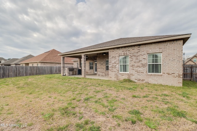 back of house with a patio area, a fenced backyard, a yard, and brick siding