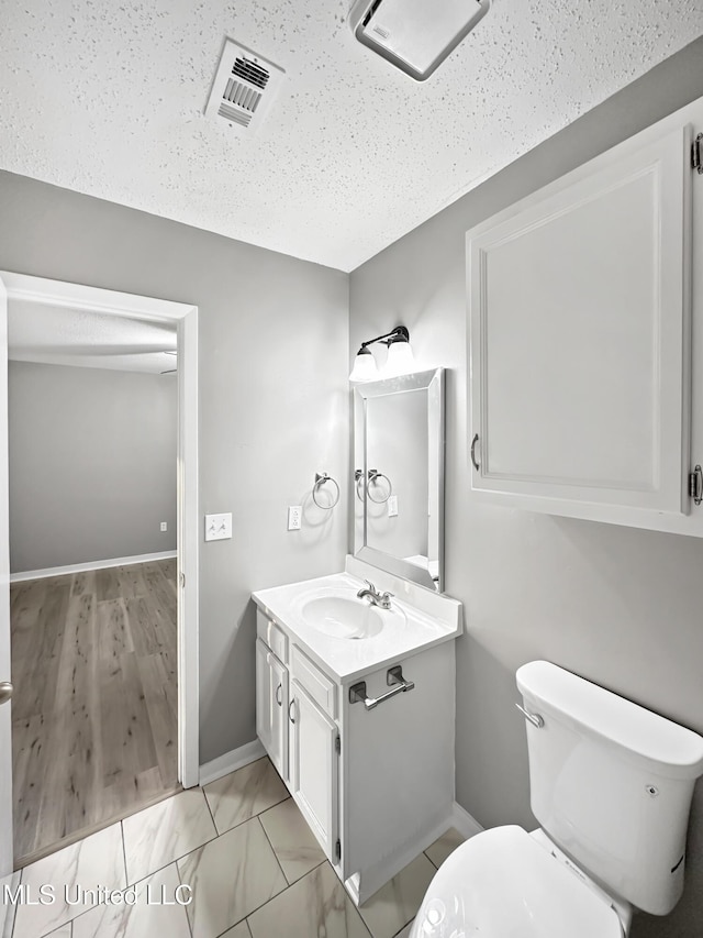 bathroom featuring vanity, a textured ceiling, and toilet