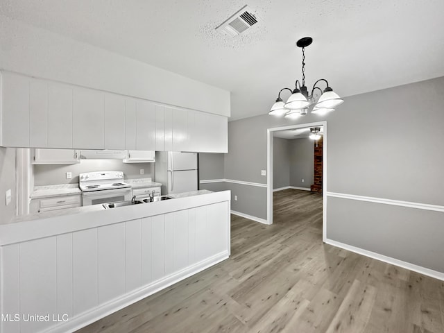 kitchen featuring white cabinetry, hanging light fixtures, light hardwood / wood-style floors, kitchen peninsula, and white appliances