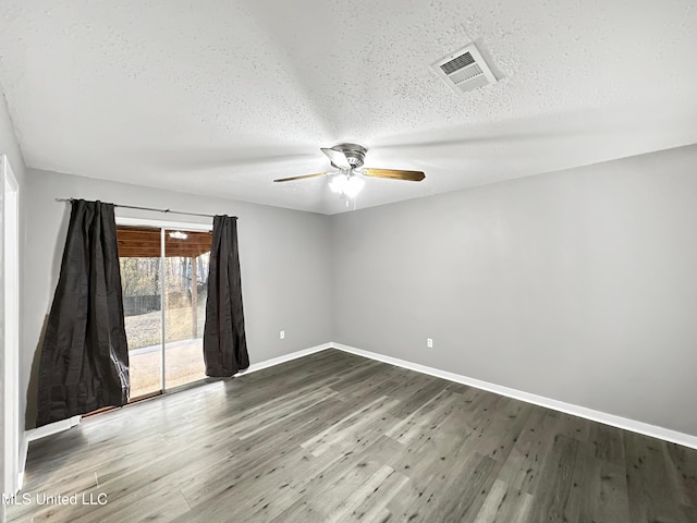 empty room with ceiling fan, dark hardwood / wood-style flooring, and a textured ceiling