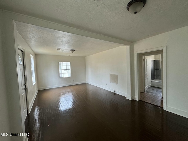 unfurnished room featuring baseboards, a textured ceiling, and dark wood-style floors