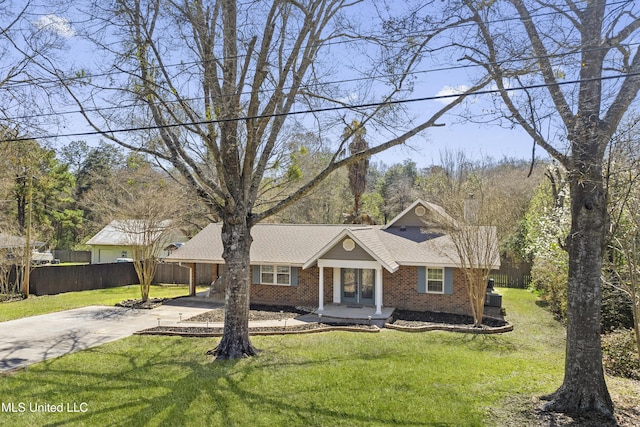 view of front facade with concrete driveway, fence, brick siding, and a front yard