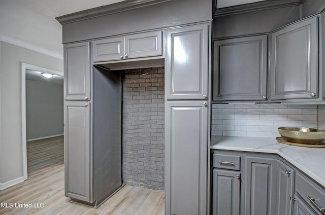 1201 Manchester Dr, Clinton, MS 39056 - kitchen with light stone counters, light wood finished floors, backsplash, gray cabinetry, and ornamental molding