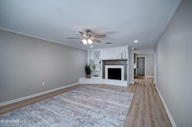 1201 Manchester Dr, Clinton, MS 39056 - unfurnished living room with ceiling fan, crown molding, a brick fireplace, baseboards, and light wood-style flooring