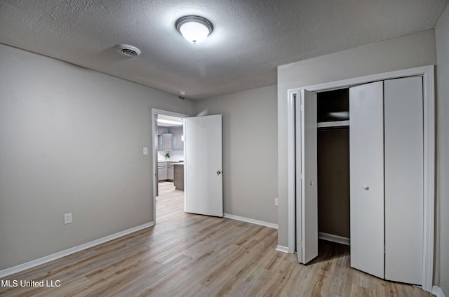1201 Manchester Dr, Clinton, MS 39056 - unfurnished bedroom featuring a closet, a textured ceiling, baseboards, and light wood-style floors