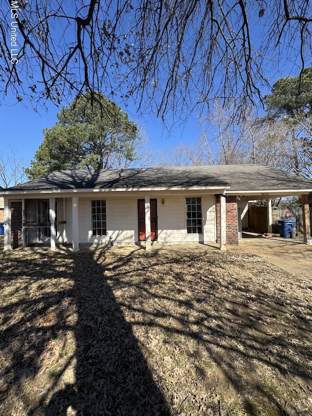 exterior space with driveway, a carport, and brick siding