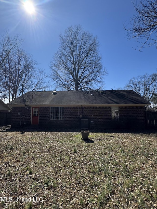 rear view of property featuring brick siding and fence